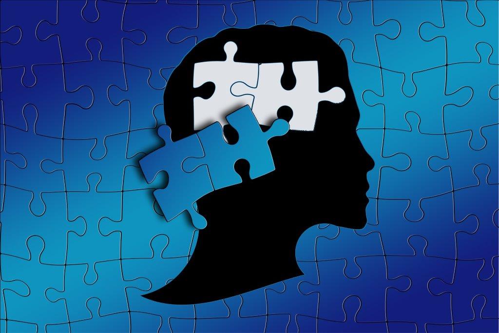 Puzzle mit Menschenkopf im Profil, wo zwei Puzzleteile dort fehlen, wo das Gehirn ist
